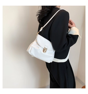 Detail of white pleated PU leather shoulder bag with gold metal buckle closure on a model