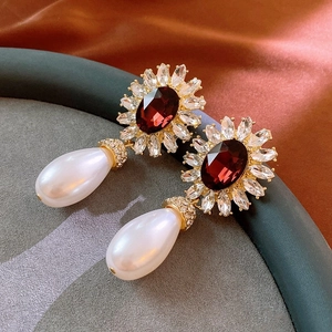 Détail de boucles d'oreilles fleur rouge avec perle goutte sur fond en soie