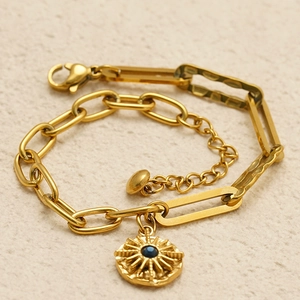 Dettaglio del bracciale a graffetta placcato oro 18K con ciondolo a sole e gemma blu