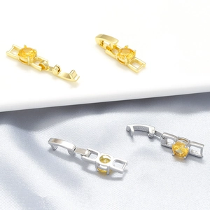 Detailed view of heart-shaped fold-over clasps in gold and silver with yellow gemstones