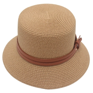 Detail of paper straw boater hat featuring a dark brown faux leather band and metallic buckle