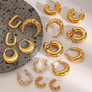 Various luxury gold geometric hoop and zircon studded earrings on dark volcanic stone