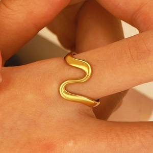 Macro shot of a golden wavy minimalist ring showing polished texture and elegant fit