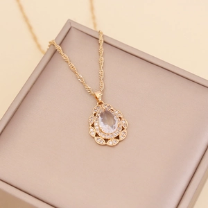Golden teardrop necklace with crystal pendant on a beige jewelry box lid