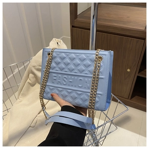 Detail of blue embossed crossbody bag featuring gold chain and FASHION lettering
