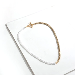 Detailed view of bicolor toggle clasp necklace with white pearls and gold metal beads