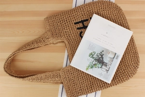 Détail du sac cabas en paille tissée avec broderie H noire et texture de style vacances