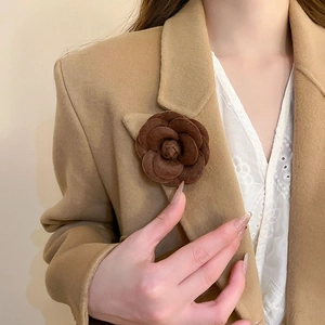 Close-up of a brown camellia flower brooch pinned on a beige blazer lapel