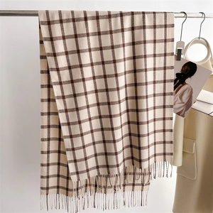 Close-up of beige and brown plaid scarf featuring elegant tassel fringe details
