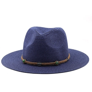 Detail of navy straw sun hat featuring brown braided band with green beads and metal charms