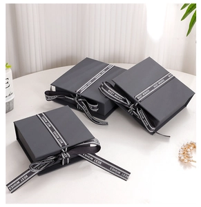 Close-up of dark grey square flip jewelry gift box with a black Best Wishes ribbon