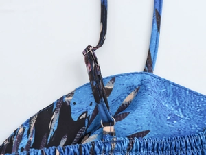 Detail of adjustable thin strap on blue floral print top with metal buckle and pleats