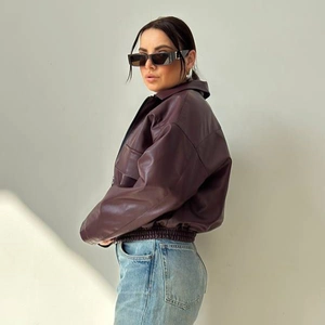 Vista laterale di una donna in giacca biker in pelle bordeaux con vita sfiancata