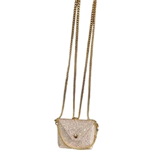 Macro detail of golden glitter envelope bag with metallic button and chain strap