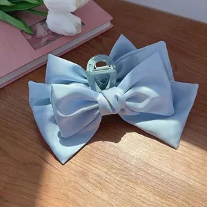 Gros plan d'une pince à cheveux à double nœud en satin bleu clair sur table en bois