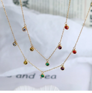 Close-up of gold chain necklace featuring colorful round rhinestone pendants in macro detail
