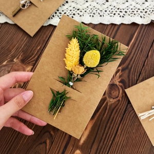 Detailed view of handmade kraft paper card with yellow dried flowers and green leaves