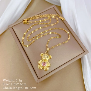 Macro shot of gold bear pendant necklace with pink heart gemstone in a premium jewelry box