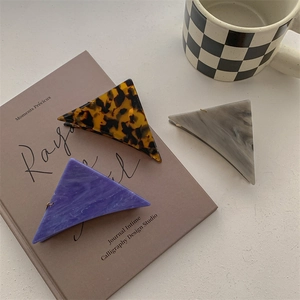 Three minimalist triangular resin hair claws in tortoise shell and marble patterns