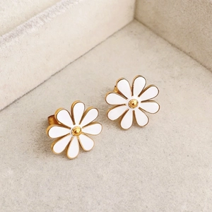 Elegant white daisy stud earrings with gold center on soft grey jewelry display