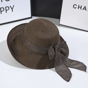 Detail of dark brown woven straw hat with wide ribbon bow and raw fringe edges