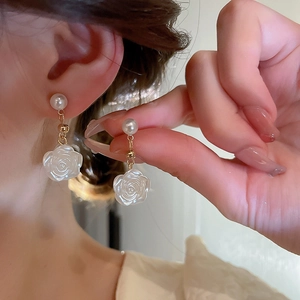 Boucles d'oreilles camélia blanc en acrylique avec perle fantaisie sur mannequin