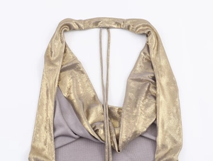 Close-up of golden metallic textured fabric stitched with grey knit on halter top neck