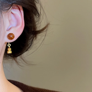 Gros plan de boucles d'oreilles gourde vintage avec perles brunes et fini doré sur modèle