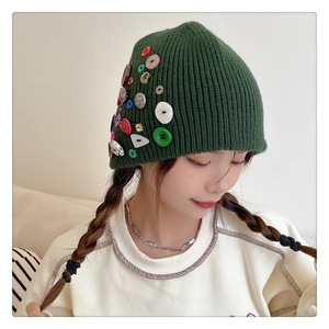 Detailed close-up of dark green knit beanie featuring colorful decorative buttons on the side