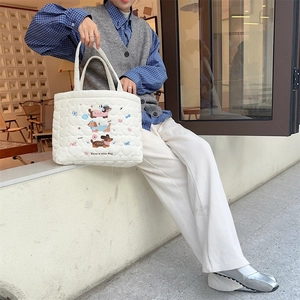 Detail of white quilted tote bag featuring dachshund embroidery and soft cotton texture