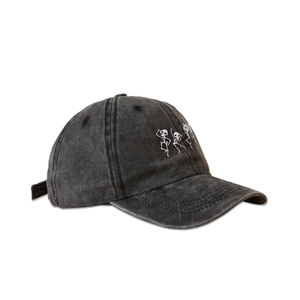 Close-up detail of white skull embroidery on black washed cotton baseball cap texture