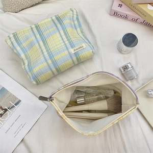 Detail of colorful plaid makeup bag set with open interior and metal zipper closure