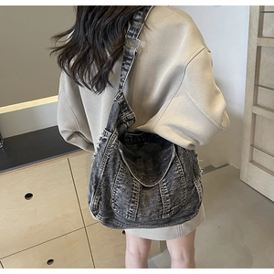Détail du sac bandoulière en denim lavé montrant la texture usée et la boucle en métal