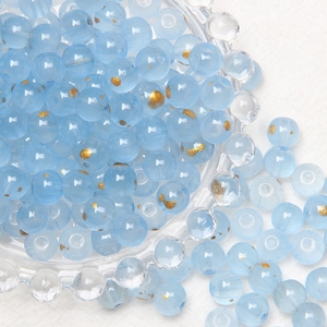 Close-up of 8mm light blue glass beads with gold speckles in a clear decorative bowl