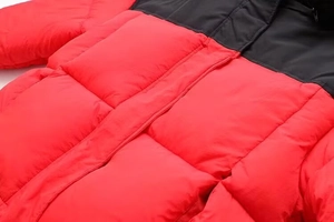 Détail de la doudoune matelassée rouge et noire montrant la texture du tissu