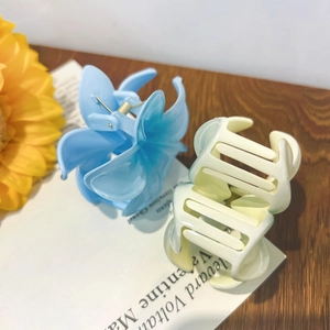 Pastel candy-colored plumeria flower hair claws in light blue and beige on a book