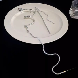 Silver snake hair pin with red eyes, crystal tassels and wing charm on a ceramic tray