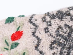 Close-up of floral embroidery and leopard jacquard pattern on oatmeal knitwear fabric