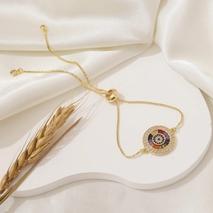Detailed shot of an adjustable gold evil eye bracelet with colorful zirconia on silk
