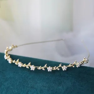 Dettaglio di un cerchietto dorato con fiori di perle bianche e design a vite su velluto