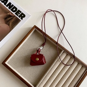 Macro shot of a red leather mini handbag pendant necklace on a wooden jewelry tray