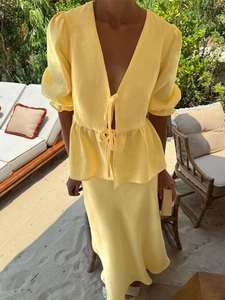 Detail of light yellow linen two-piece set featuring V-neck wrap top and ruffle hem