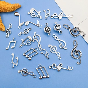 Detailed flat lay of silver musical note charms with crystal accents on a blue background