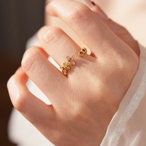 Details eines Vintage-Goldrings mit vierblättrigen Blumenmustern und roten Zirkonia