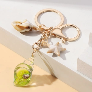 Detailed view of luminous starfish and conch seashell keychain with gold hardware