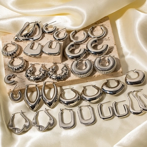 Minimalist silver stainless steel hoop earrings collection on silk background