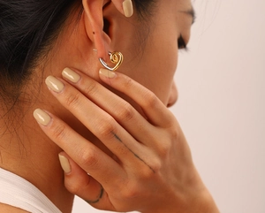 Gros plan de boucles d'oreilles cœur torsadé bicolore montrant le fini or et argent