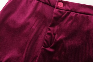 Macro shot of plush burgundy velvet fabric texture and seam detailing on suit trousers
