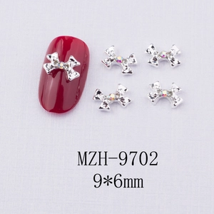 Gros plan de bijoux d'ongles nœuds argentés 9x6mm avec strass sur ongle rouge