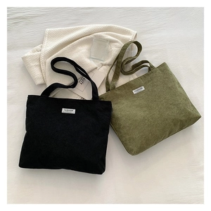 Detail view of large corduroy tote bags in black and army green with Fashion labels